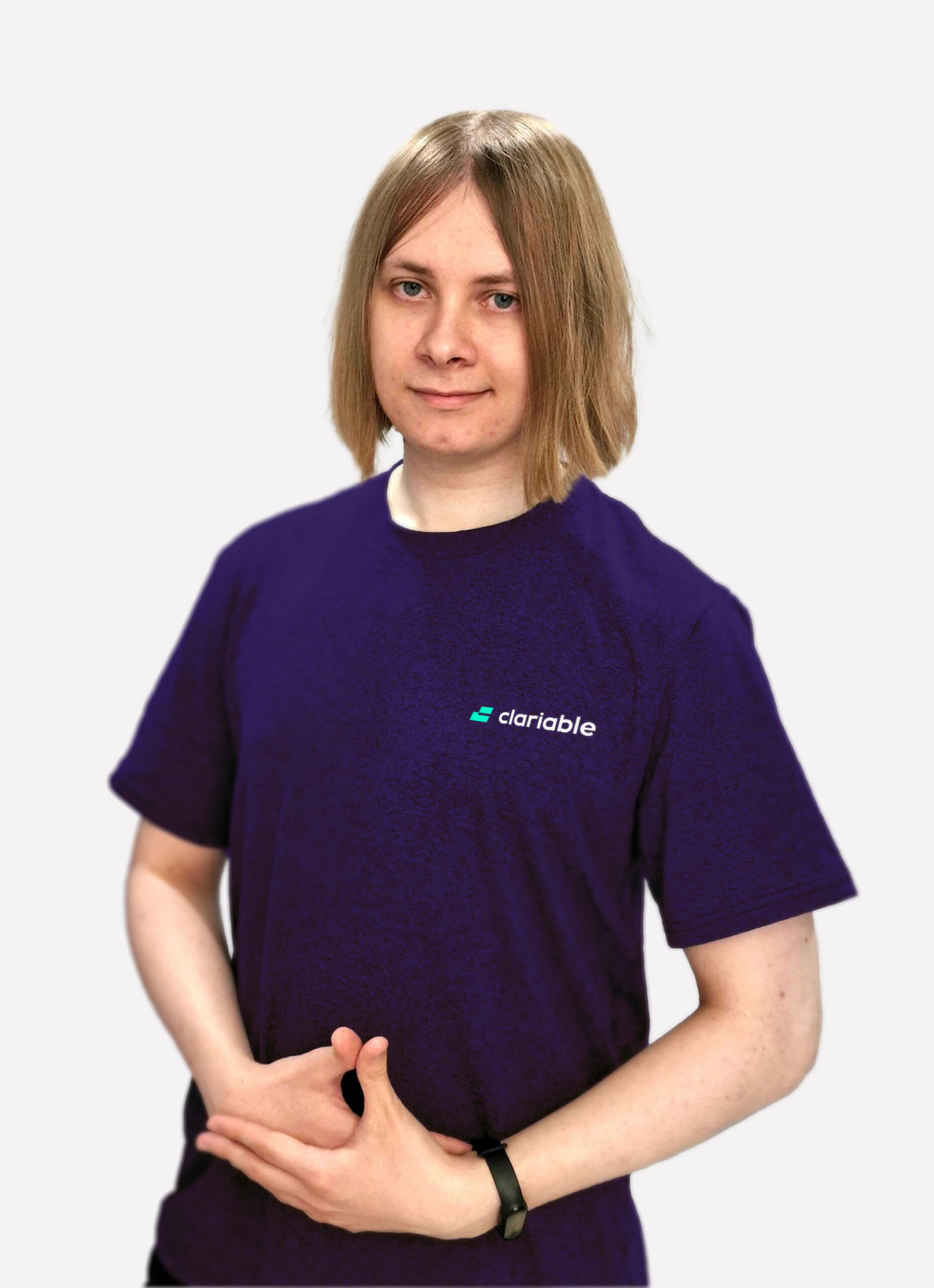 Stanislav Person with shoulder-length blonde hair wearing a purple "Clariable" t-shirt, standing against a plain white background, with hands clasped together in front.